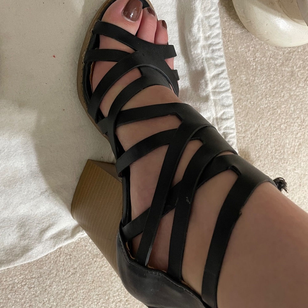 Strappy black sandal with wood like block heel.